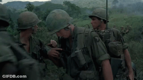 A Group Of Soldiers Wearing Green Uniforms And Helmets Are Standing In A Field GIF