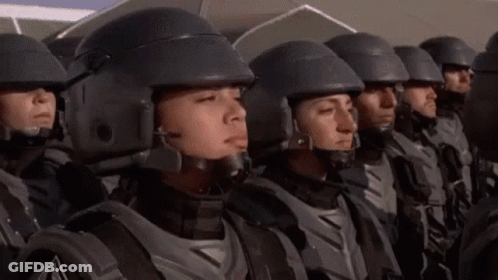 A Group Of Soldiers Wearing Helmets Are Standing In A Line . GIF