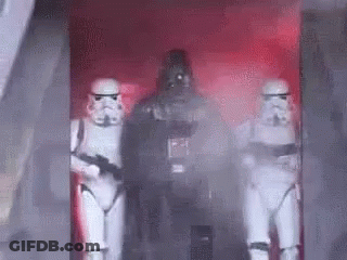 A Group Of Stormtroopers And Darth Vader Are Standing In A Room . GIF