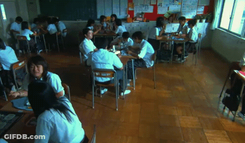 A Group Of Students Are Sitting At Their Desks In A Classroom With A Bulletin Board Behind Them GIF