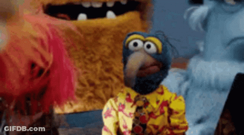 A Group Of Stuffed Animals Are Standing Next To Each Other And One Of Them Is Wearing A Yellow Shirt And Tie . GIF