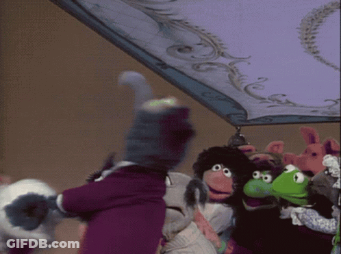 A Group Of Stuffed Animals Are Standing Under A Purple Blanket GIF