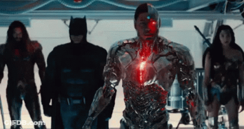 A Group Of Superheros Standing Next To Each Other In A Room . GIF
