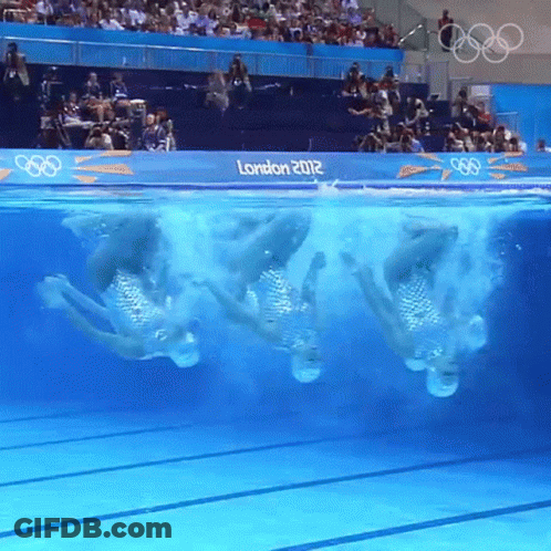 A Group Of Synchronized Swimmers Are Performing In A Pool With A Sign That Says London 2012 GIF