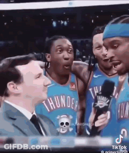A Group Of Thunder Basketball Players Are Talking To A Man In A Suit . GIF