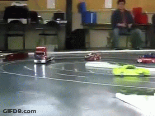 A Group Of Toy Cars Are Racing On A Track In A Room GIF