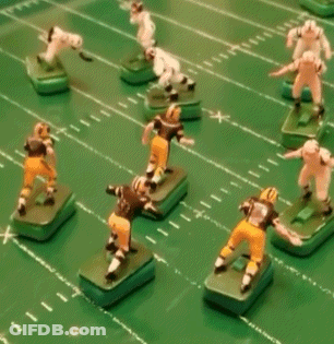 A Group Of Toy Football Players On A Green Field With One Wearing A Black Jersey With The Number 9 On It GIF