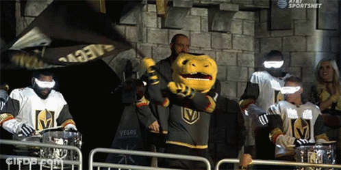 A Group Of Vegas Golden Knights Hockey Players Standing Behind A Fence With A Mascot . GIF