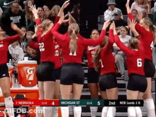 A Group Of Volleyball Players Are Giving Each Other A High Five In Front Of A Crowd . GIF