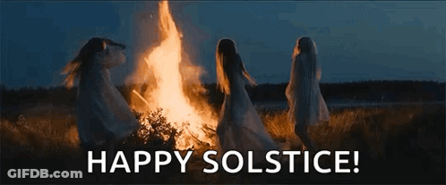 A Group Of Women Are Dancing Around A Fire In A Field At Night . GIF
