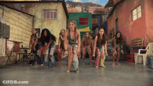 A Group Of Women Are Dancing Barefoot In Front Of A Building That Says ' Tnt ' On It GIF