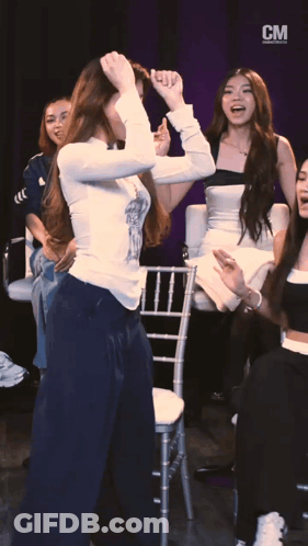 A Group Of Women Are Dancing In Front Of A Cm Banner GIF