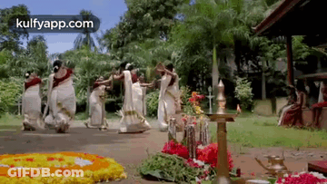 A Group Of Women Are Dancing In Front Of A Floral Display . GIF