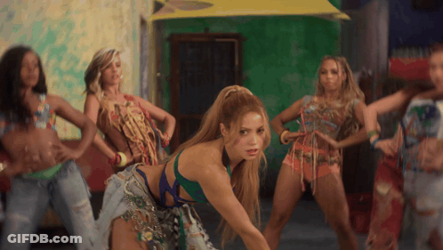 A Group Of Women Are Dancing In Front Of A Green Wall And A Yellow Umbrella GIF
