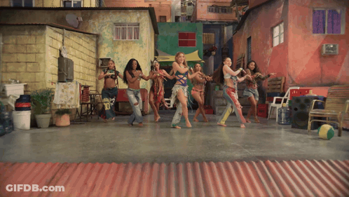 A Group Of Women Are Dancing In Front Of A Red Wall GIF