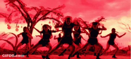 A Group Of Women Are Dancing In Front Of A Tree With A Red Sky In The Background GIF