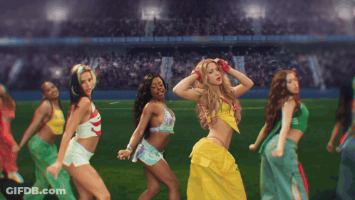 A Group Of Women Are Dancing On A Field And One Of Them Is Wearing A Yellow Skirt GIF