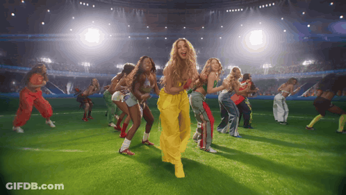 A Group Of Women Are Dancing On A Field In Front Of A Crowd GIF