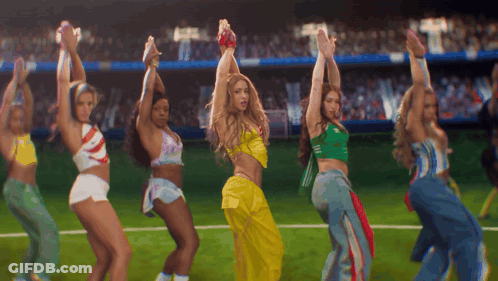 A Group Of Women Are Dancing On A Field With Their Hands In The Air GIF