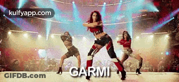 A Group Of Women Are Dancing On A Stage In Front Of A Crowd And The Word Garmi Is On The Bottom . GIF