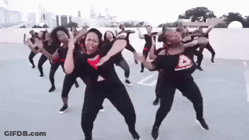 A Group Of Women Are Dancing Together On A Parking Lot . GIF