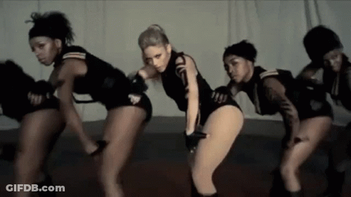 A Group Of Women Are Dancing Together On A Stage In A Room . GIF