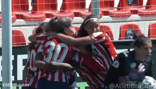 A Group Of Women Are Hugging Each Other On A Soccer Field . One Of The Players Has The Number 30 On Her Jersey . GIF