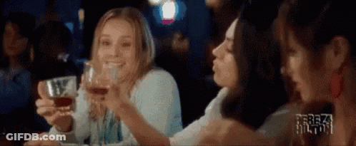 A Group Of Women Are Sitting At A Table Drinking Wine And Toasting . GIF