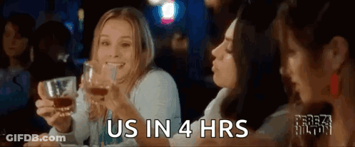 A Group Of Women Are Sitting At A Table Holding Glasses Of Whiskey And Toasting . GIF