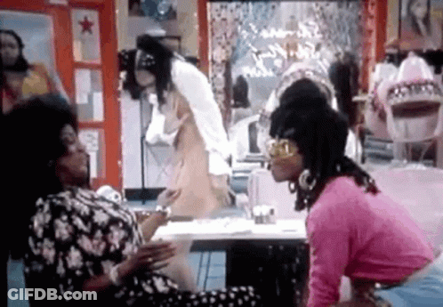 A Group Of Women Are Sitting At A Table Talking To Each Other In A Room . GIF