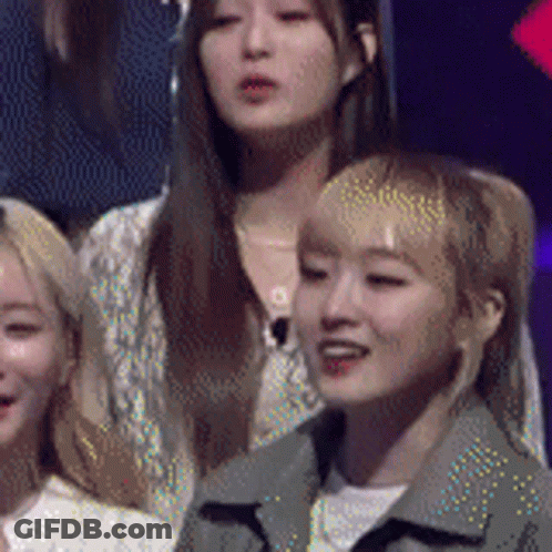 A Group Of Women Are Sitting In A Row And One Of Them Is Looking At The Camera . GIF