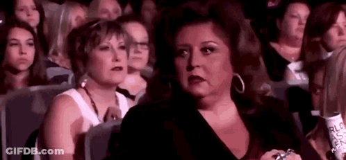 A Group Of Women Are Sitting In A Theatre Watching A Show . GIF