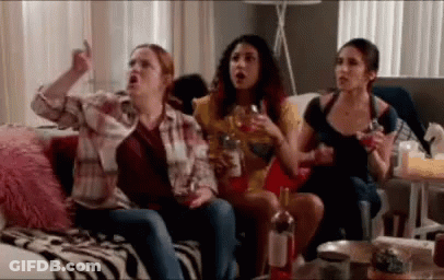 A Group Of Women Are Sitting On A Couch Drinking Wine And Watching Tv . GIF