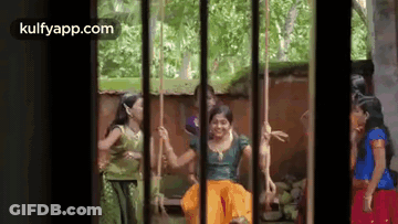 A Group Of Women Are Sitting On Swings In A Cage . GIF