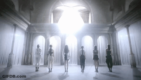 A Group Of Women Are Standing In A Room With White Curtains And A Light Shining Through The Curtains . GIF