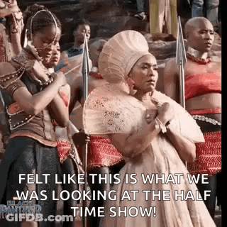 A Group Of Women Are Standing Next To Each Other In A Line Holding Spears And A Fan . GIF