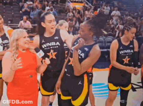 A Group Of Women Are Standing On A Basketball Court And One Of Them Is Wearing A Wnba Jersey . GIF