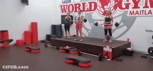 A Group Of Women Are Standing On A Stage In Front Of A Sign That Says World Gym GIF