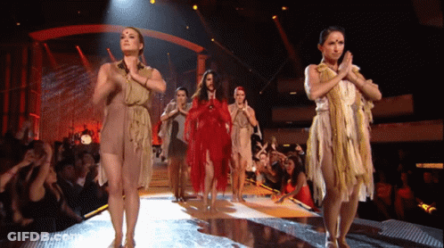 A Group Of Women Dancing On A Stage With Their Hands Together GIF