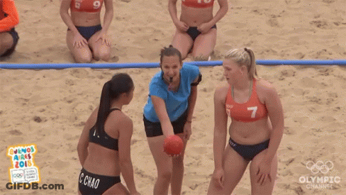 A Group Of Women In Bikinis Are Playing Handball On The Beach . GIF