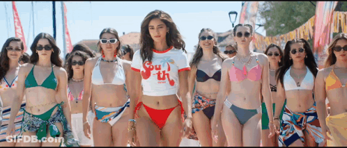 A Group Of Women In Bikinis Are Standing Next To Each Other On The Beach . GIF