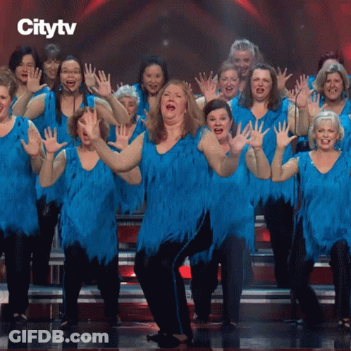 A Group Of Women In Blue Dresses Are Dancing On A Stage GIF