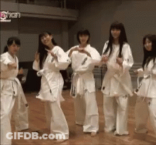 A Group Of Women In Karate Uniforms Are Dancing Together GIF