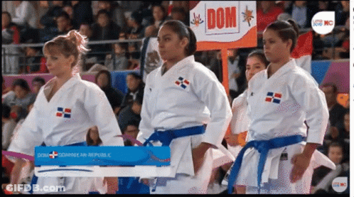 A Group Of Women In Karate Uniforms Standing In Front Of A Sign That Says Dom GIF