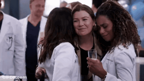 A Group Of Women In Lab Coats Hugging Each Other While Holding A Glass Of Champagne . GIF