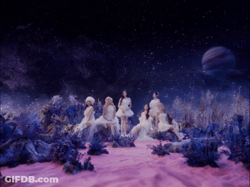 A Group Of Women In White Dresses Are Sitting In A Pink Field GIF