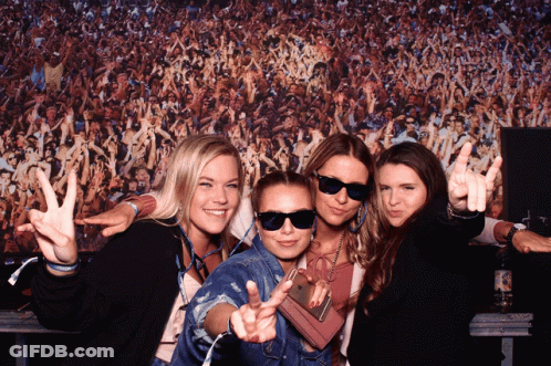 A Group Of Women Posing In Front Of A Crowd Of People GIF