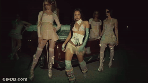 A Group Of Women Standing In Front Of A Car In A Dark Room GIF