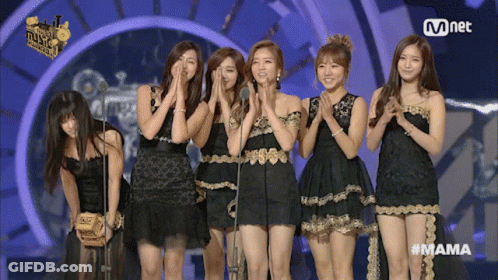 A Group Of Women Standing In Front Of A Mnet Logo On A Stage GIF