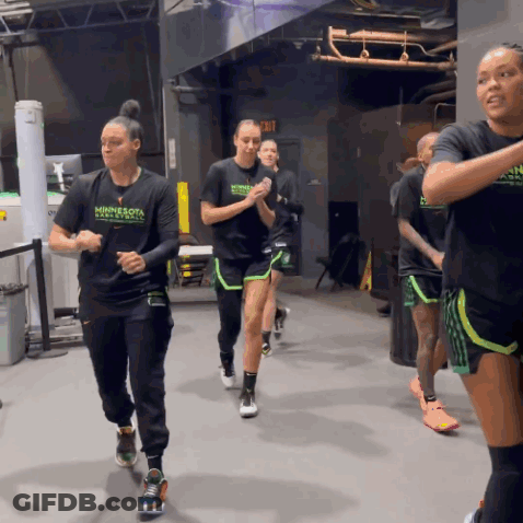 A Group Of Women Wearing Minnesota Basketball Shirts Are Running In A Gym GIF